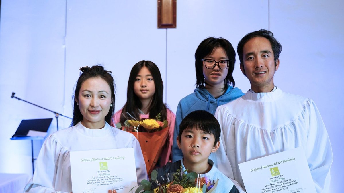 刚受洗的弟兄与太太、孩子一起站着拍照，手里拿着证书