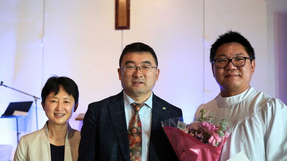 受洗的弟兄抱着花，与牧师、师母一起合照