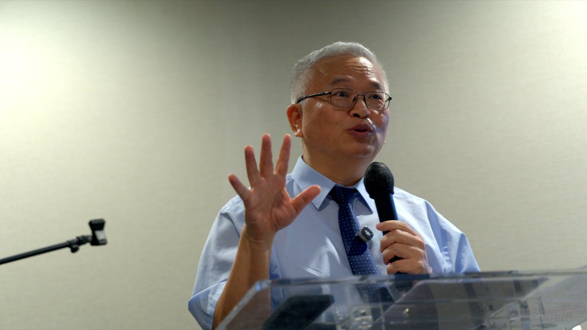 长辈拿着麦克风在台前说话
