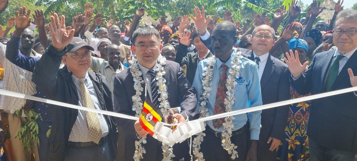 A village church opening, local pastors and visitors cutting the ribbon as the congregation raises their hands
